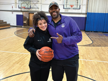 Leila Carter holding basketball and posing with basketball coach